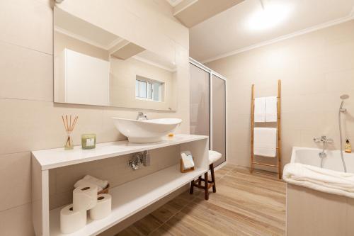 a white bathroom with a sink and a tub at Atlantis Breeze in Madalena