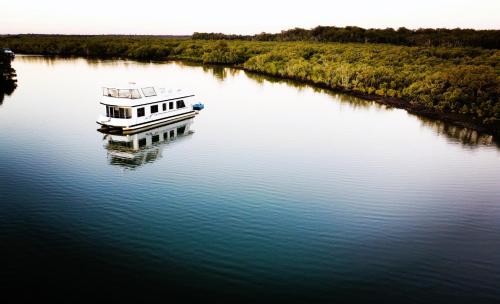 Coomera Houseboats في غولد كوست: وجود قارب يجلس على الماء في النهر