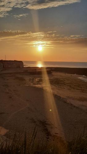a sunset on a beach with the sun setting at Home from Home Stay Margate in Margate