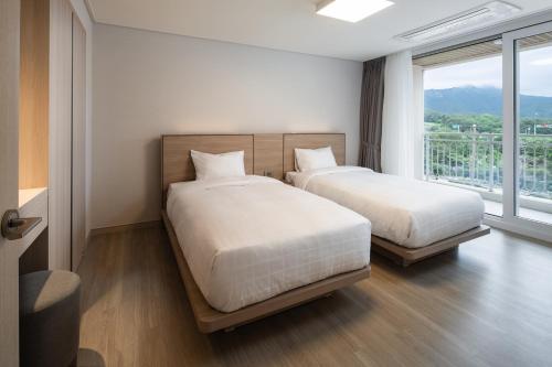 two beds in a room with a large window at Kumho Seorak Resort in Sokcho