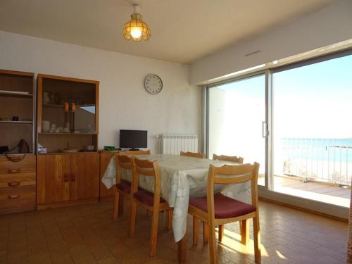 une table à manger avec des chaises et une horloge murale dans l'établissement Palavas F2 cabine dernier étage, double terrasse, parking privé - FR-1-559-22, à Palavas-les-Flots
