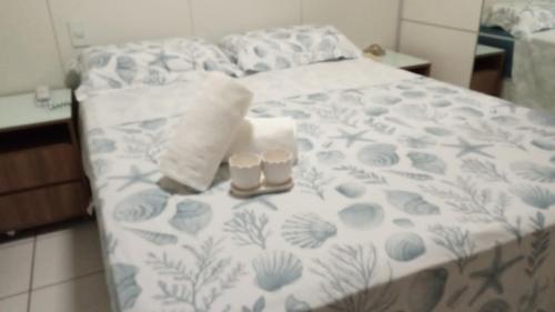 a bed with two cups and a towel on it at Gran Lençóis Flat Residence in Barreirinhas