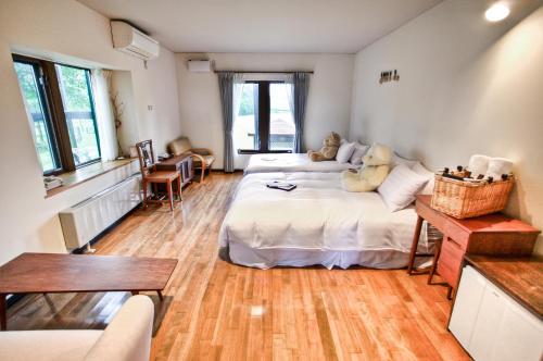 a large room with two beds and a table at Adagio Hokkaido in Biei