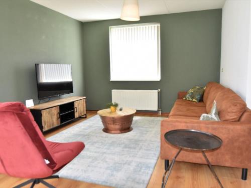 a living room with a couch and a tv at Holiday Home in Flevoland with Pool in Zeewolde