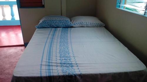 a bed with two pillows on it in a room at Waikiki Guest House in Treasure Beach