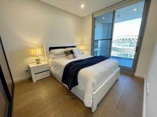 sypialnia z łóżkiem i dużym oknem w obiekcie Olympic Park Delight Parking Pool Views Amazing Location w mieście Sydney