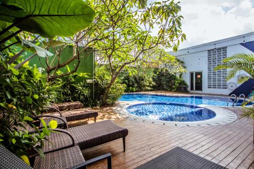 a swimming pool in a garden with benches and trees at Tjokro Style Yogyakarta in Yogyakarta