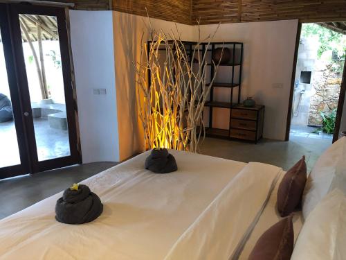 a bedroom with a large white bed with black pillows at Kayuma Villas Lombok in Selong Belanak