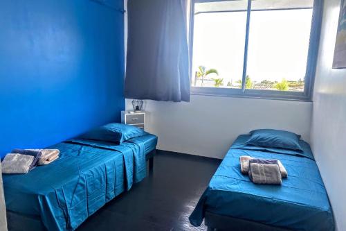 two beds in a room with blue walls and windows at Villa Tiki - wonderfull sea view in Punaauia
