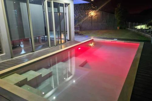 a swimming pool with red lighting in a house at night at Villa Tiki - wonderfull sea view in Punaauia