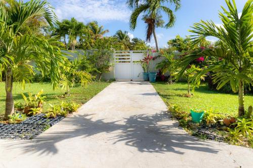 a driveway leading to a garage with palm trees at Villa L'Artist en bord de mer avec piscine privée in Sainte-Rose