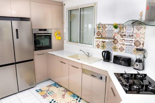 a white kitchen with a sink and a refrigerator at Villa L'Artist en bord de mer avec piscine privée in Sainte-Rose