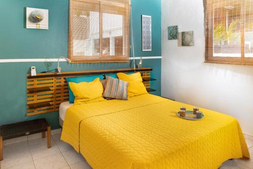 una camera con letto e copriletto giallo di Villa L'Artist en bord de mer avec piscine privée a Sainte-Rose