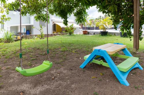 a swing set with a table and a bench at Villa L'Artist en bord de mer avec piscine privée in Sainte-Rose