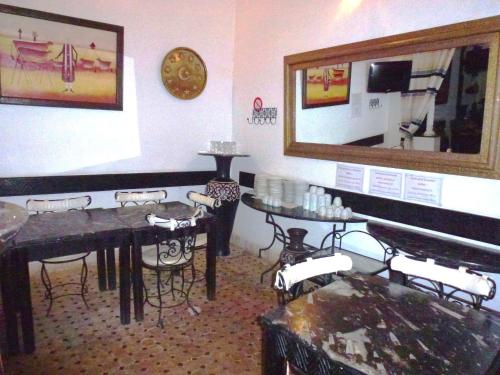een eetkamer met tafels en stoelen en een spiegel bij Ryad Laârouss in Marrakesh