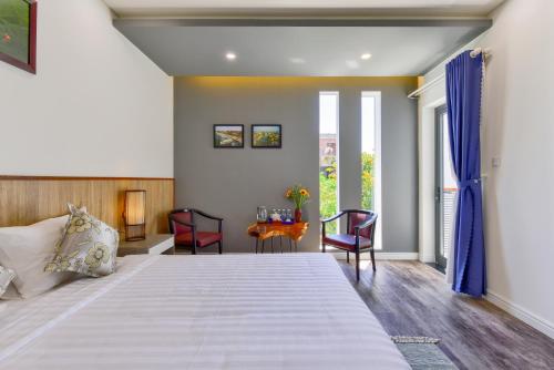 a bedroom with a large bed and a table at Aroma Garden Suites Hoi An in Hoi An