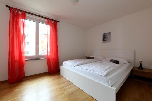 1 dormitorio con 1 cama con cortinas rojas y ventana en Locarno Garden & E-scooters en Muralto