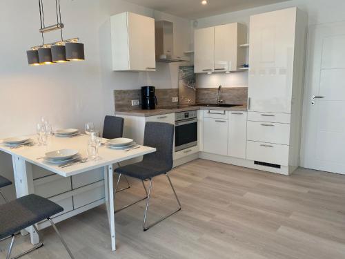 a kitchen with white cabinets and a table and chairs at Steinwarder 9 - Haus "Seeschwalbe" ST9 017 Steinwarder 9 in Heiligenhafen