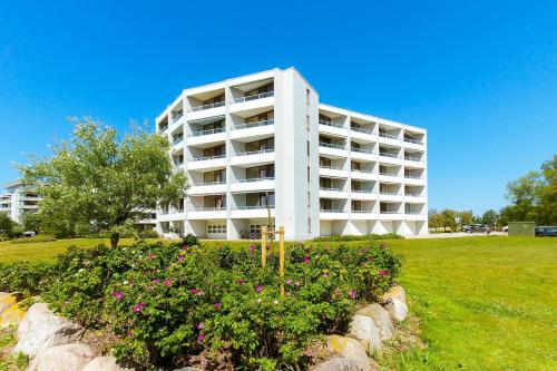 a white apartment building with flowers in a garden at Steinwarder 1 - Haus "Seerose" ST1 034 Steinwarder 1 in Heiligenhafen
