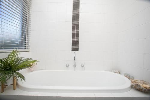 a white bath tub in a bathroom with a plant at "WATERLILY HOUSE" - Luxury Canal House, Jetty, Dog & Child Friendly - Sleeps 14 in Mandurah