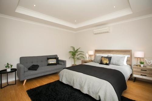 a bedroom with a large bed and a couch at "WATERLILY HOUSE" - Luxury Canal House, Jetty, Dog & Child Friendly - Sleeps 14 in Mandurah