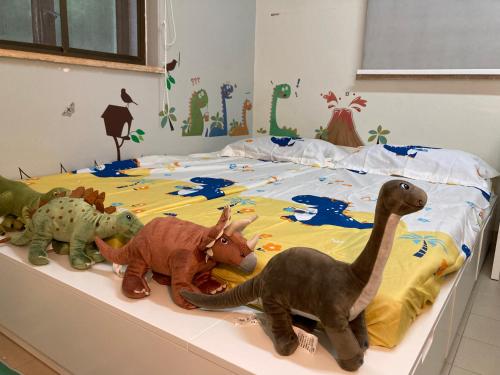 three stuffed dinosaurs are sitting on a bed at YHA Ngong Ping SG Davis Youth Hostel in Hong Kong