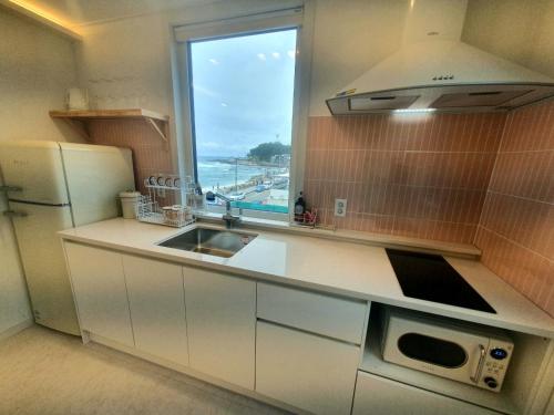 a kitchen with a sink and a window at Mr. Slow in Sokcho