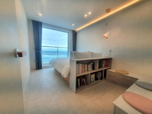 a bedroom with a bed and a book shelf with a window at Mr. Slow in Sokcho