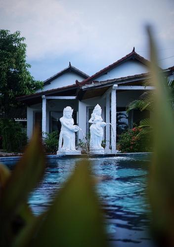 two white statues in front of a house at Salt Resort & Spa in Amed