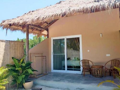 a patio of a house with chairs and a thatch roof at BeachWalk Koh Rong in Koh Rong Island