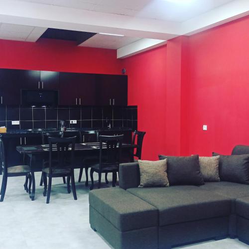 a living room with a red wall and a table and chairs at Hotel SESIL in Gyumri