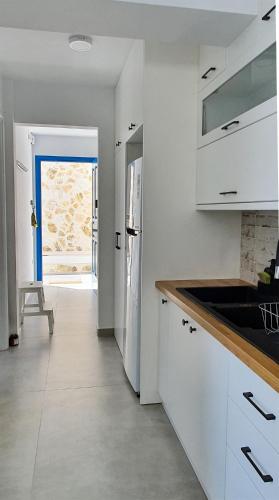 a kitchen with white cabinets and a door leading to a patio at Meraki Beachfront in Foinikion
