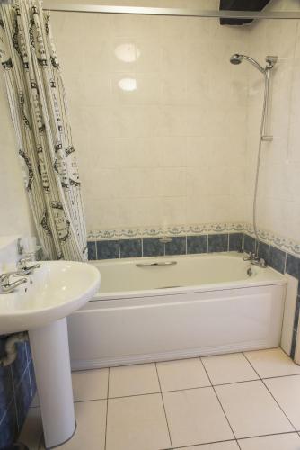 a bathroom with a tub and a sink and a bath tub at The New Inn by Roomsbooked in Gloucester