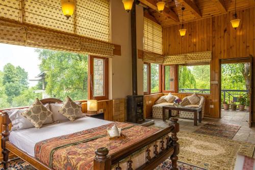 a bedroom with a bed in a room with windows at StayVista at The Waterwillow with Valley View in Manāli