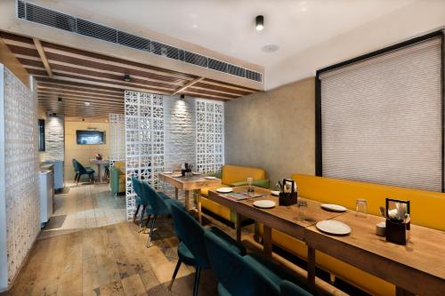 a restaurant with wooden tables and green chairs at Poiisse in Kolkata