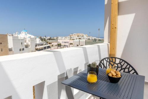 a table on a balcony with a glass of orange juice at Alenor City Hotel in Naxos Chora