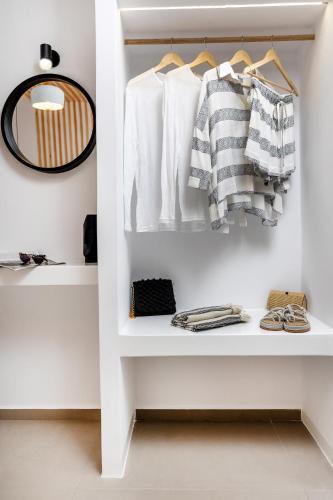 a white closet with white shirts and a mirror at Alenor City Hotel in Naxos Chora