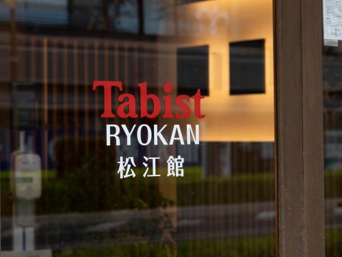 a sign on a glass door with a train at Tabist Matsuekan in Matsue