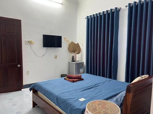 a bedroom with a bed with blue sheets and blue curtains at Tulip Mui Ne in Phan Thiet