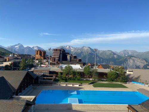 a resort with a swimming pool and mountains in the background at Superbe Studio avec vue exceptionnelle in L'Alpe-d'Huez