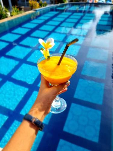 a person holding a yellow drink in front of a pool at Salt Resort & Spa in Amed