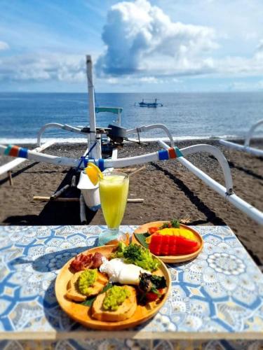 a table with a plate of food and a drink at Salt Resort & Spa in Amed