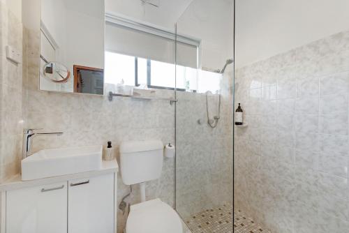 uma casa de banho com um WC e uma cabina de duche em vidro. em Fi's Beach Pad em Port Macquarie