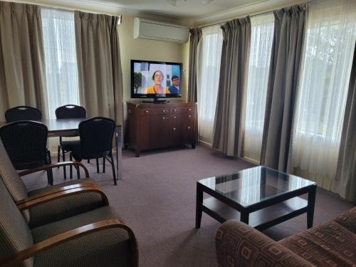 a living room with a television and a table and chairs at Titania Motel in Oberon