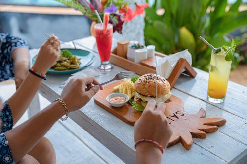 two people sitting at a table eating a sandwich and fries at Salt Resort & Spa in Amed