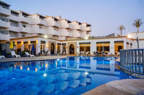 a hotel with a swimming pool in front of a building at Odyssee Park Hotel in Agadir