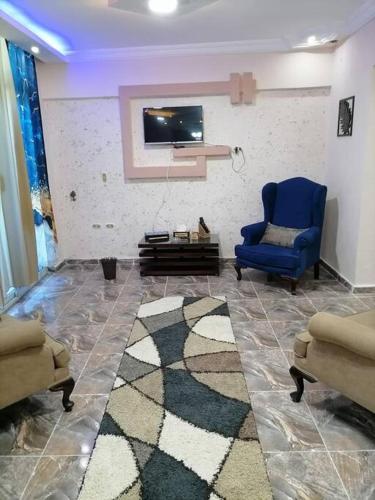 a living room with a blue chair and a tv at Sea spirit in Alexandria