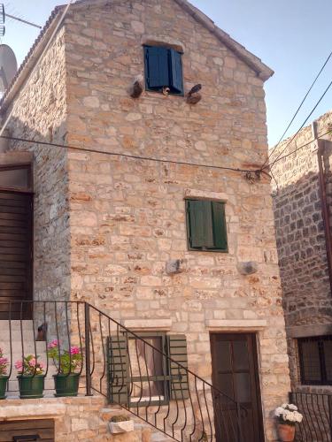 a stone house with two windows and a staircase at Stone house Castellum in Kaštela