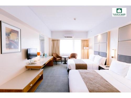 a hotel room with two beds and a desk at Sotogrande Hotel and Resort in Mactan