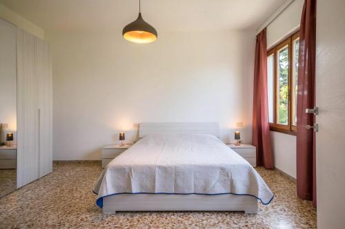 um quarto com uma cama branca, 2 mesas e uma janela em Casa vacanze Bergamo em Cavallino-Treporti